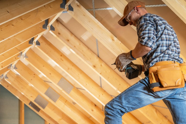 Construction worker installing beams in attic space
